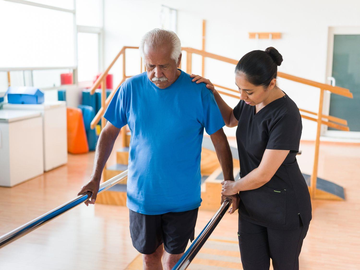 Physiotherapist assisting elderly patient with balance and mobility exercises at home