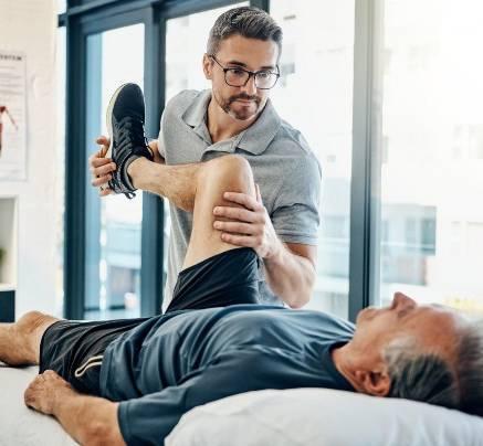 Physiotherapist performing knee rehabilitation exercises with a patient in a home setting