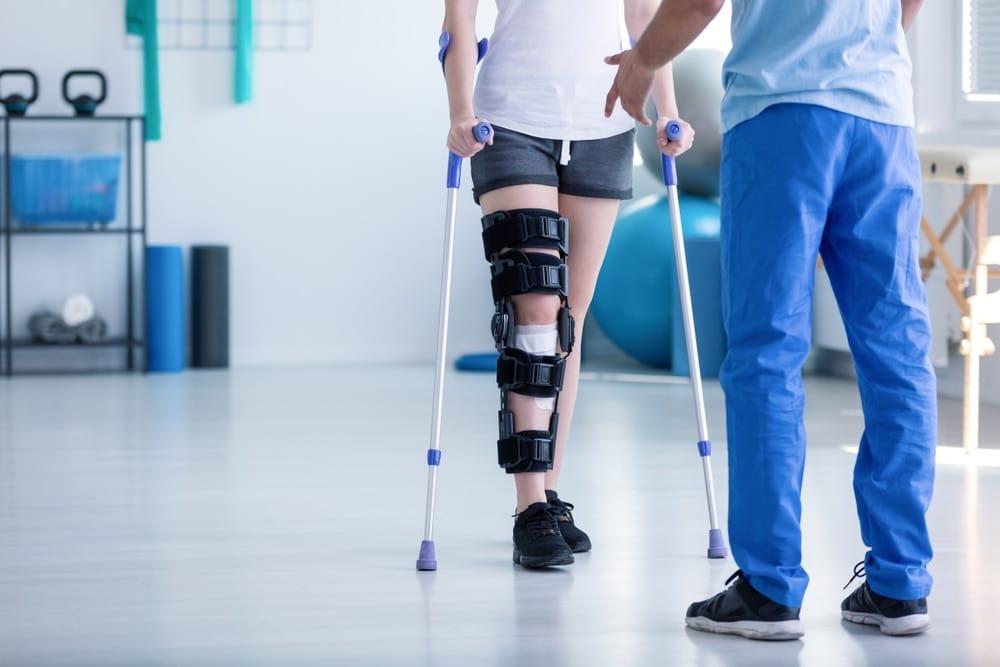 Physiotherapist assisting patient with post-surgery rehabilitation exercises at home